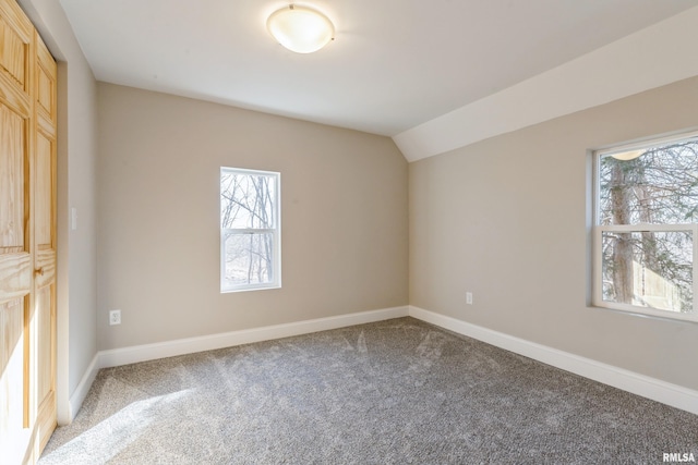 unfurnished room with baseboards, plenty of natural light, lofted ceiling, and light carpet