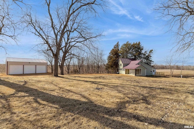 view of yard with an outdoor structure, a garage, and dirt driveway