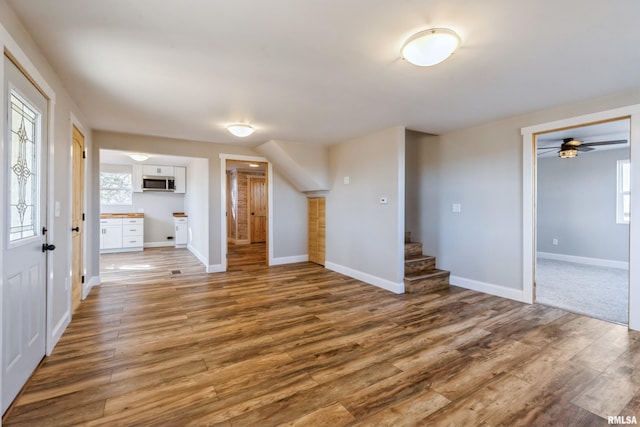 interior space with stairs, wood finished floors, and baseboards