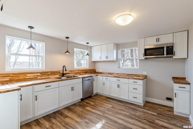 kitchen with a sink, stainless steel appliances, dark wood-style flooring, and wood counters