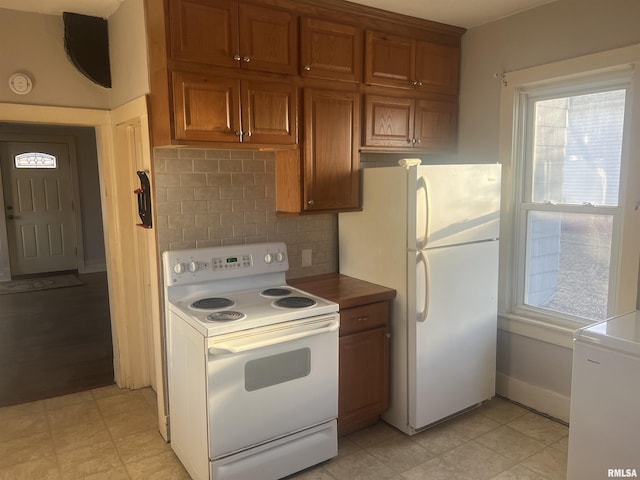 kitchen with decorative backsplash, white appliances, brown cabinetry, and baseboards