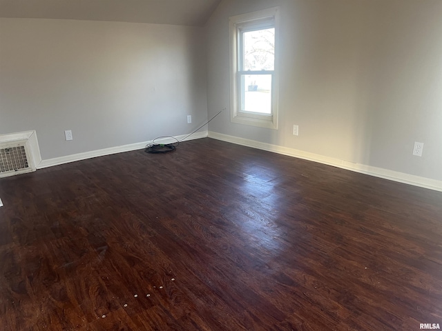 interior space featuring baseboards, lofted ceiling, and dark wood-style flooring