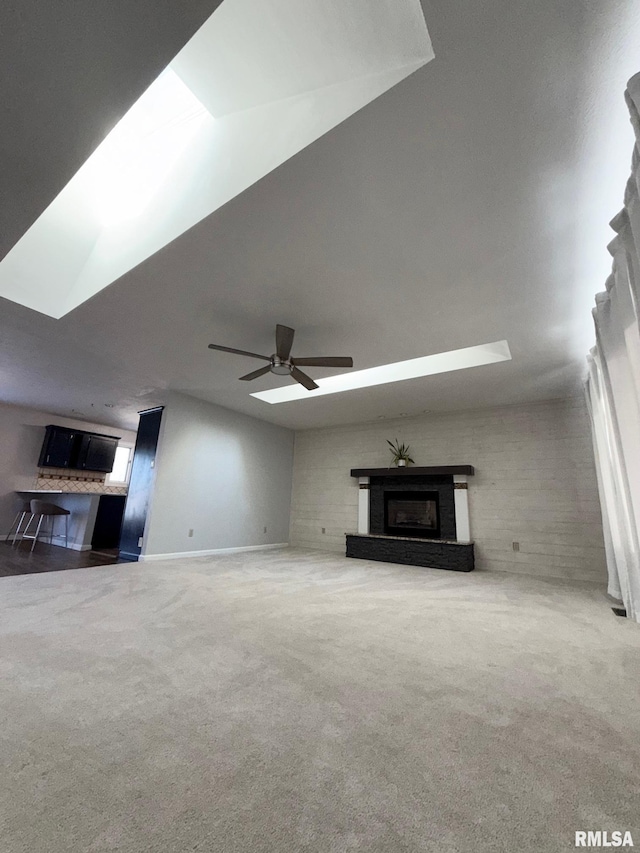 unfurnished living room with carpet, a fireplace with raised hearth, and a ceiling fan