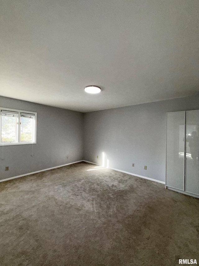 carpeted spare room featuring baseboards