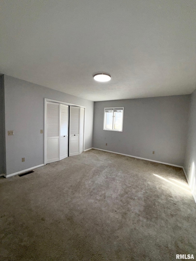 unfurnished bedroom featuring visible vents, baseboards, a closet, and carpet flooring