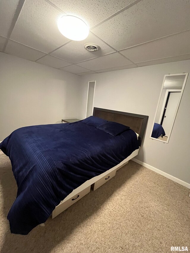 carpeted bedroom with visible vents, baseboards, and a drop ceiling