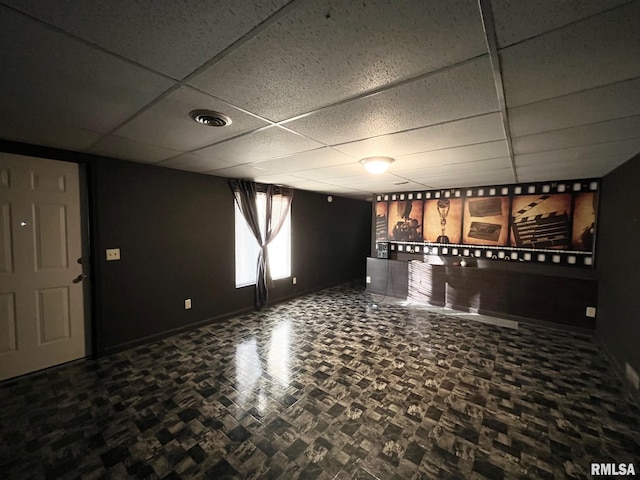 interior space featuring baseboards, a paneled ceiling, and visible vents