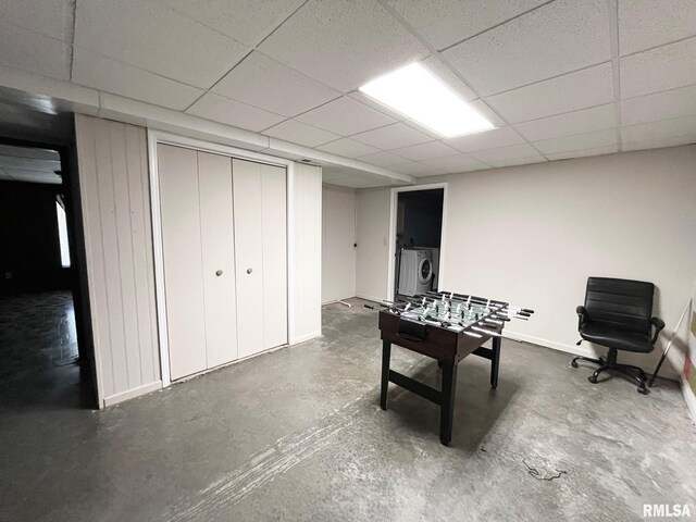 playroom with concrete floors, a drop ceiling, baseboards, and independent washer and dryer