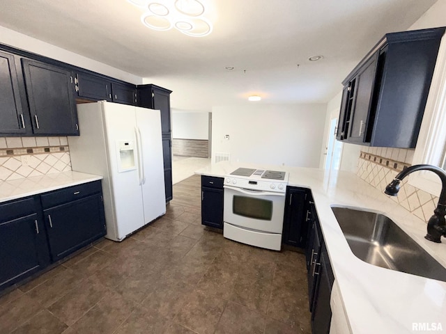 kitchen with a sink, white appliances, a peninsula, light countertops, and dark cabinets