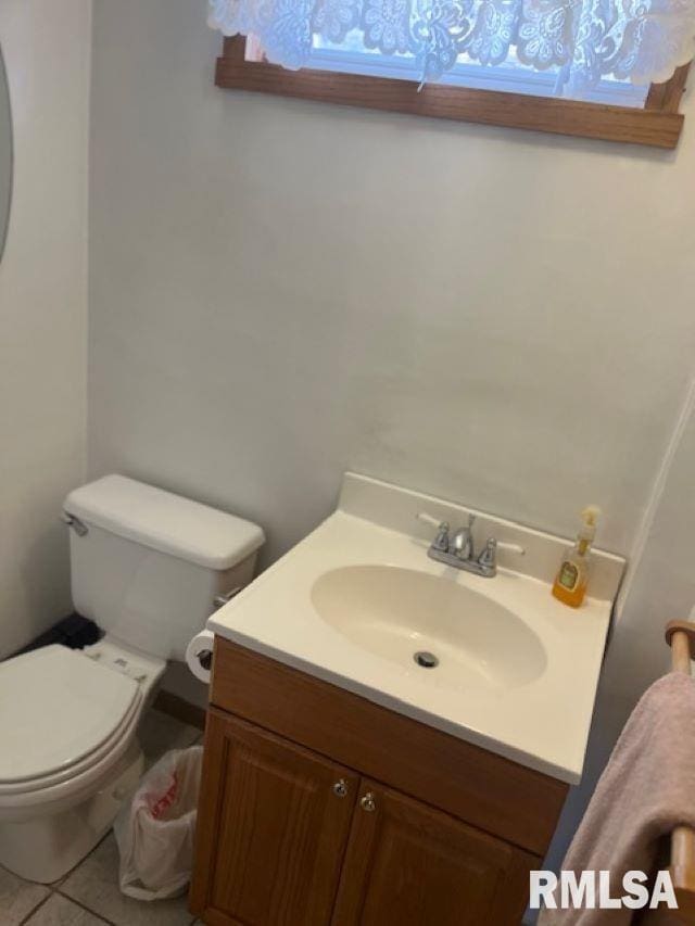 half bath with vanity, toilet, and tile patterned flooring