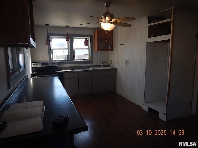 kitchen with dark wood-type flooring, stainless steel range with electric stovetop, a sink, decorative light fixtures, and dark countertops