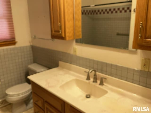 bathroom featuring a wainscoted wall, toilet, and vanity