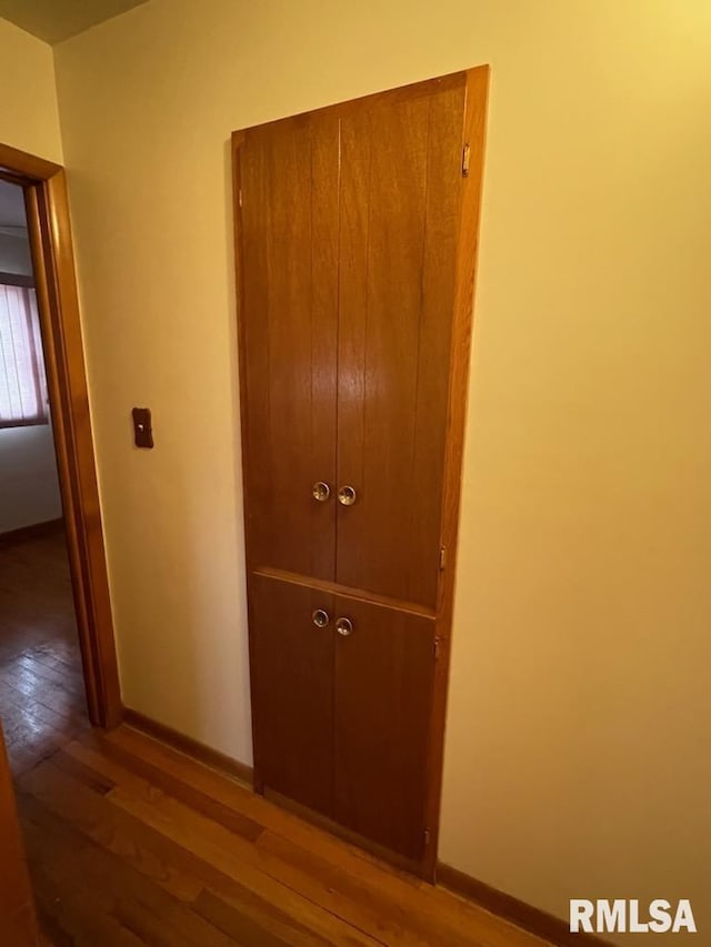 corridor with baseboards and hardwood / wood-style flooring