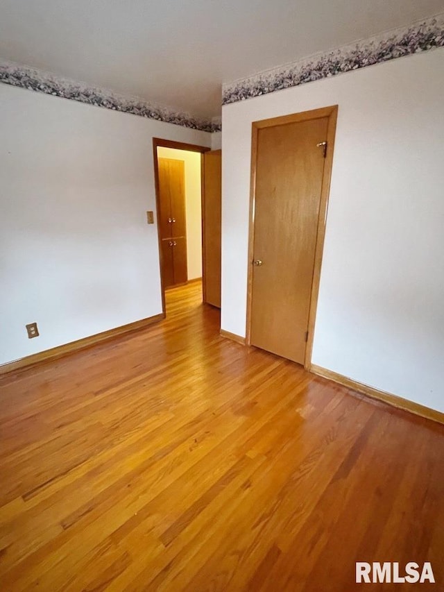 empty room featuring light wood finished floors and baseboards