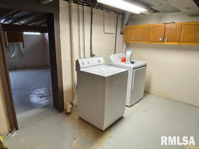 washroom featuring cabinet space, separate washer and dryer, and concrete block wall