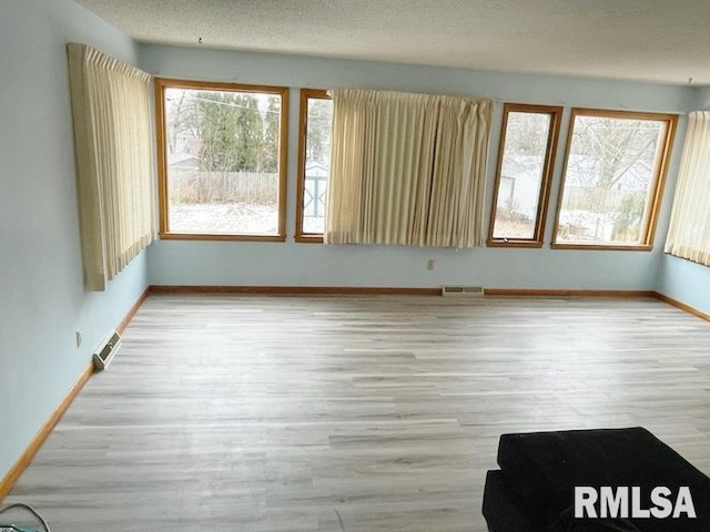 empty room with visible vents, baseboards, a textured ceiling, and wood finished floors