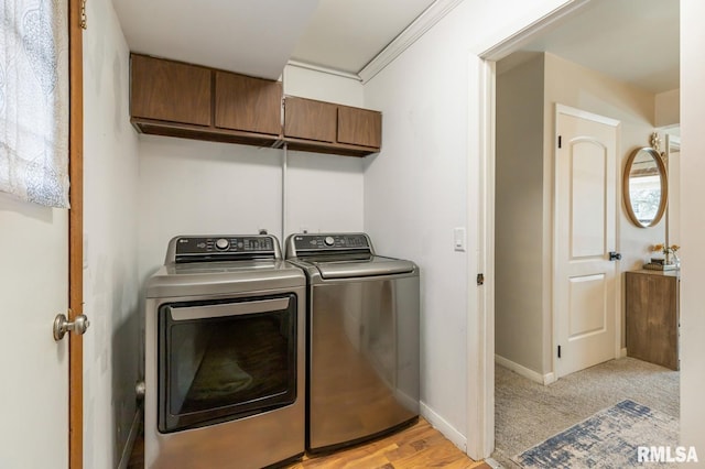 washroom with cabinet space, baseboards, and washing machine and dryer