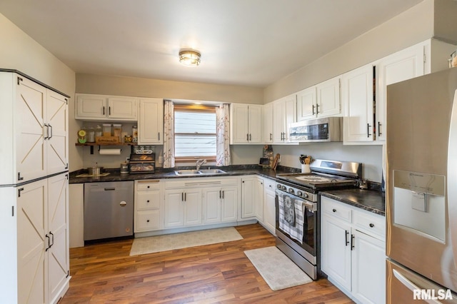 kitchen with a sink, dark countertops, wood finished floors, and stainless steel appliances