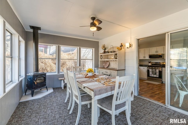 dining room with a ceiling fan and a wood stove