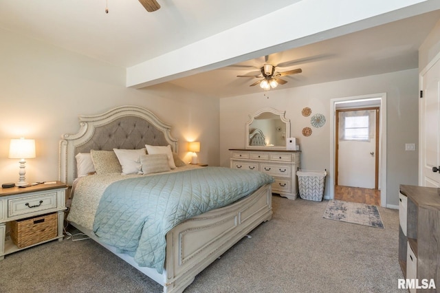 carpeted bedroom with beam ceiling and a ceiling fan