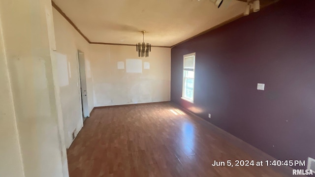 unfurnished room with baseboards, an inviting chandelier, wood finished floors, and ornamental molding