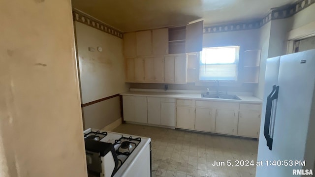 kitchen featuring a sink, white appliances, white cabinets, light countertops, and light floors