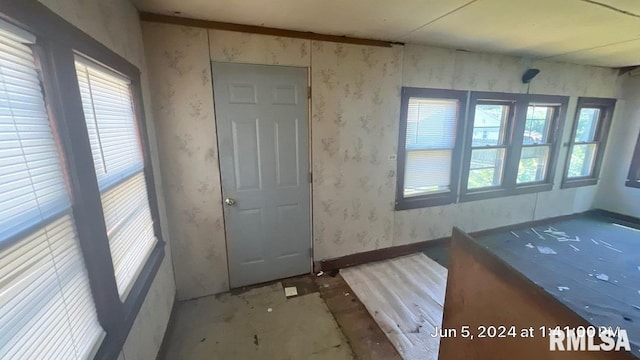 interior space featuring wallpapered walls and baseboards