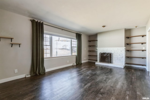 unfurnished living room with visible vents, baseboards, a brick fireplace, and dark wood-style flooring