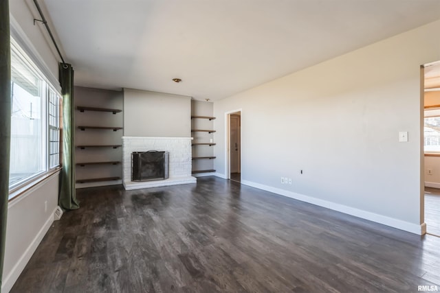 unfurnished living room featuring dark wood-type flooring, a fireplace, and baseboards