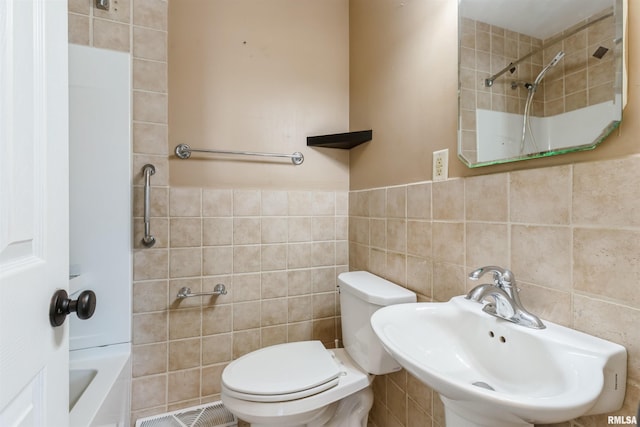 bathroom with visible vents, a sink, wainscoting, tile walls, and toilet