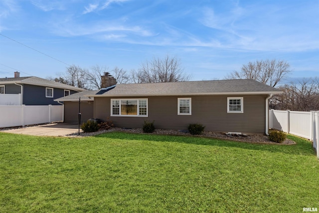 rear view of property featuring a patio, a yard, a fenced backyard, and a chimney