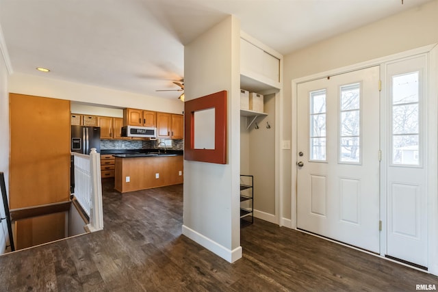 kitchen featuring brown cabinets, dark countertops, appliances with stainless steel finishes, and dark wood finished floors