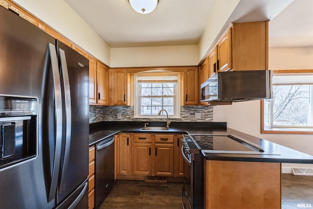 kitchen with decorative backsplash, appliances with stainless steel finishes, dark wood-type flooring, and a sink