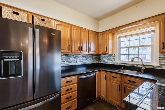 kitchen featuring a sink, dishwashing machine, stainless steel fridge, and dark countertops