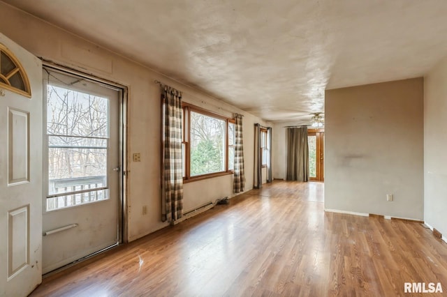 interior space featuring ceiling fan, a baseboard heating unit, and light wood-style floors