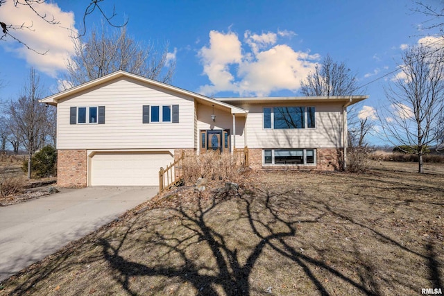 raised ranch featuring brick siding, driveway, and an attached garage