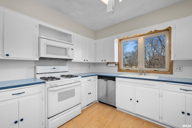 kitchen with white cabinets, white appliances, light wood-type flooring, and a sink