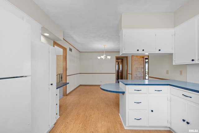 kitchen featuring a peninsula, light wood-style flooring, a notable chandelier, and white cabinets