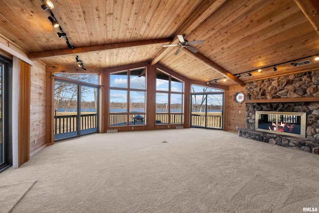 unfurnished living room with a water view, wood walls, wood ceiling, carpet floors, and a fireplace