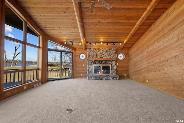 unfurnished living room featuring visible vents, wooden walls, a stone fireplace, carpet flooring, and wood ceiling