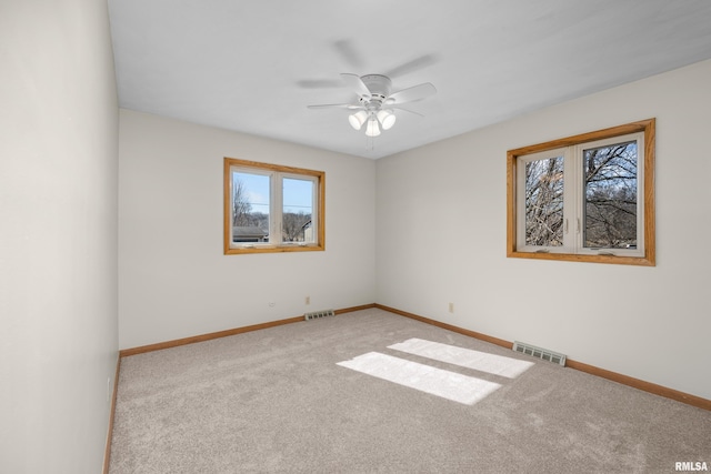 carpeted spare room featuring a ceiling fan, baseboards, and visible vents