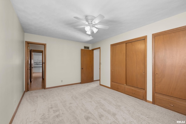 unfurnished bedroom featuring visible vents, two closets, a ceiling fan, baseboards, and light colored carpet