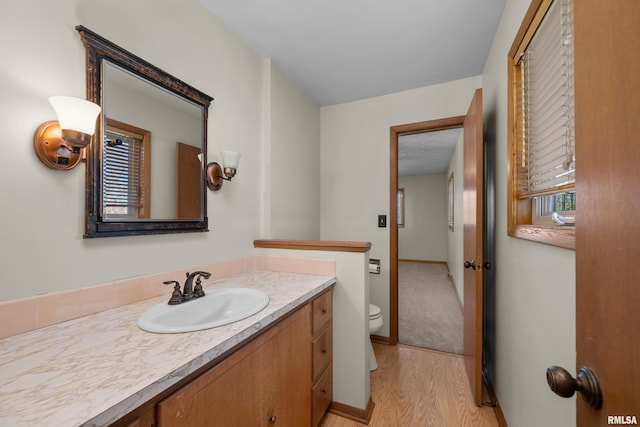 bathroom with baseboards, toilet, wood finished floors, and vanity