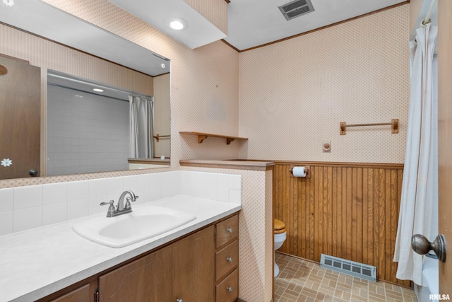 bathroom featuring visible vents, vanity, toilet, and wainscoting