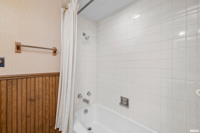 full bath featuring shower / bath combo, wainscoting, and wallpapered walls