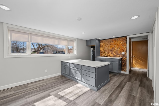 kitchen featuring baseboards, wood finished floors, gray cabinets, and light countertops