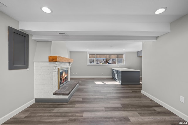 unfurnished living room featuring visible vents, dark wood-type flooring, baseboards, recessed lighting, and a fireplace