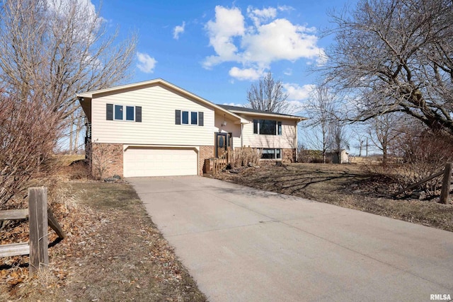 split foyer home featuring a garage, brick siding, and driveway