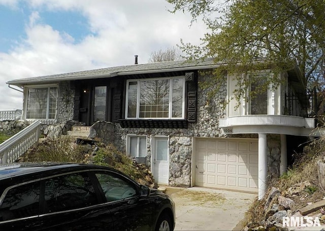 view of front facade with concrete driveway, a garage, and stone siding