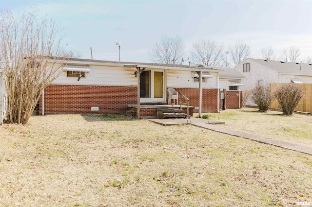 view of front of house with a front yard, fence, brick siding, and crawl space